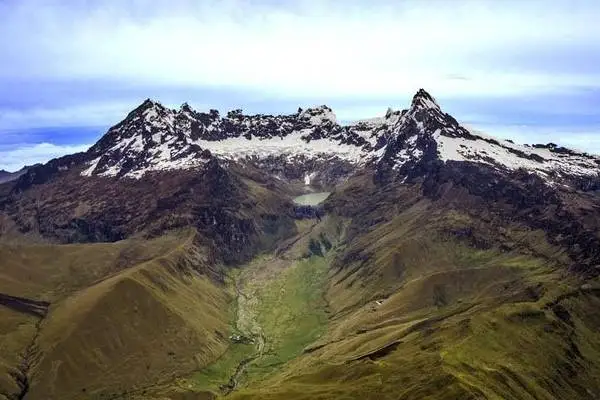 Picos nevados del volcán El Altar sobre un valle verde andino