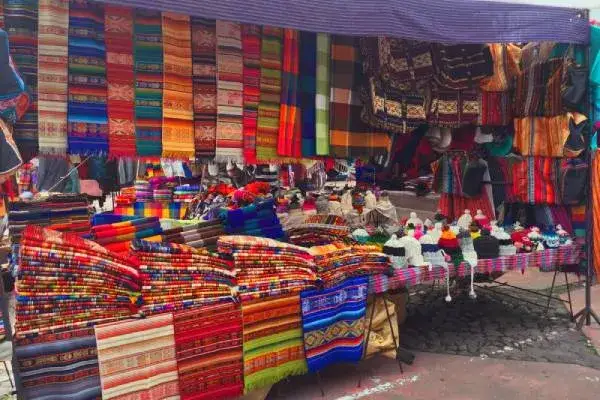 Puesto de textiles andinos de colores y gorros de lana en el mercado de Otavalo