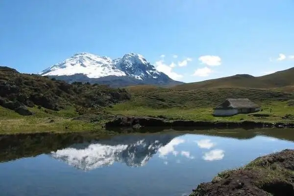 El volcán Antisana nevado se refleja en una laguna del páramo andino