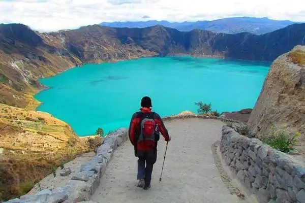 Hiker descending the trail to the turquoise Quilotoa Loop crater lake