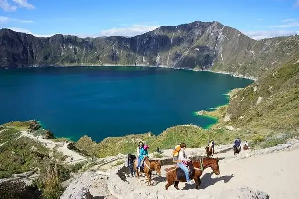 Riders on horseback along the rim trail above Quilotoa's crater lake