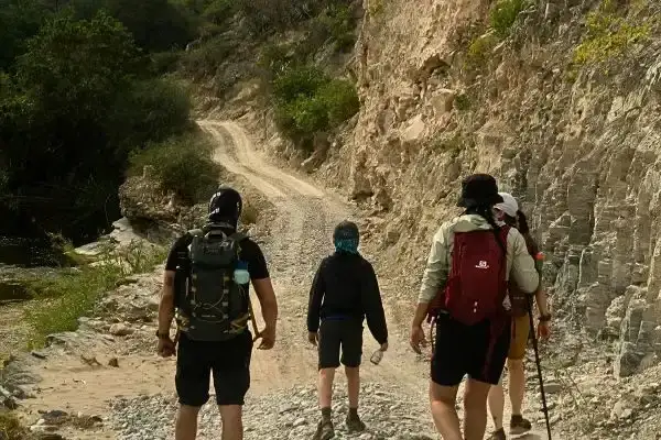 Hikers walking a dirt road through a rocky canyon on the Quilotoa to Chugchilan hike
