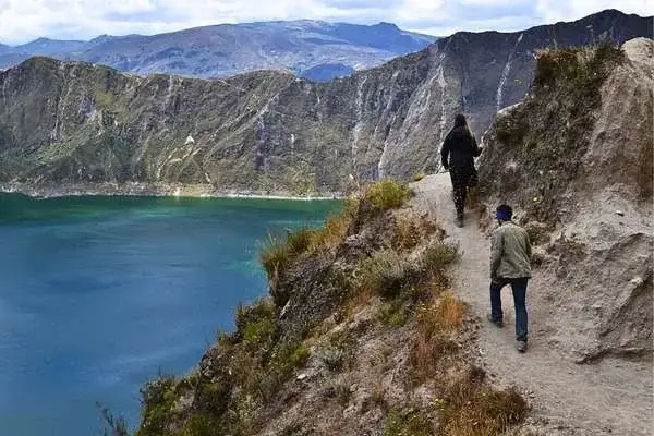 Hikers on a narrow trail along the rim of Quilotoa crater lake