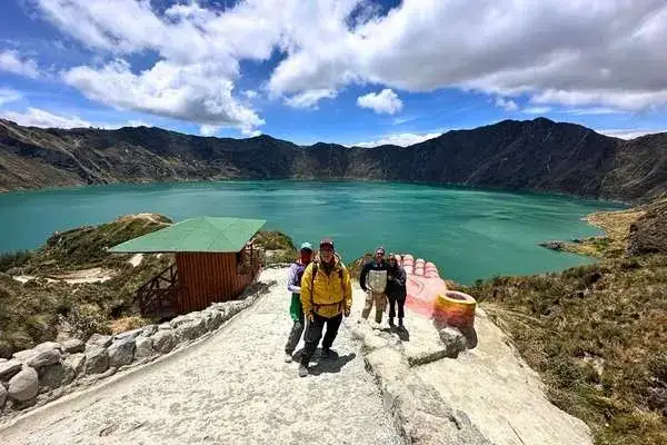 Group of hikers posing on a viewpoint above the turquoise Quilotoa crater lake