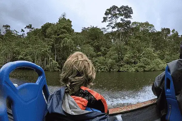 Traveler in a life jacket watching the rainforest from a canoe in Cuyabeno Reserve