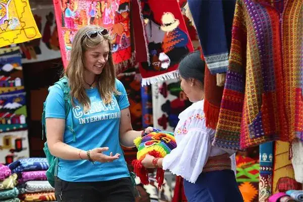 Tourist buying a handwoven Andean doll from a vendor at Otavalo Market