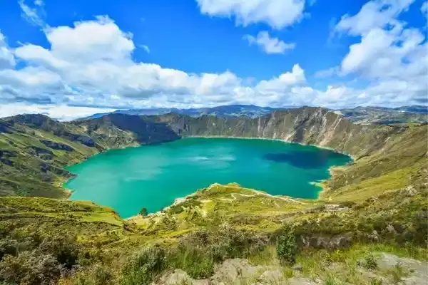 Turquoise crater lake at Quilotoa surrounded by green Andean ridges
