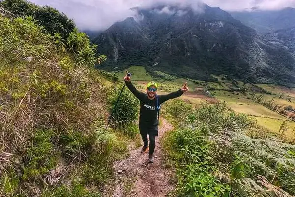 Hiker celebrating atop a cloud forest ridge during the Pululahua acclimatization hike
