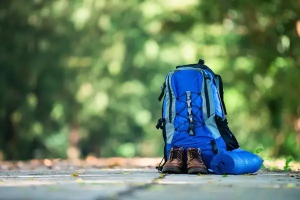 Blue hiking backpack with trekking boots resting on a forest trail