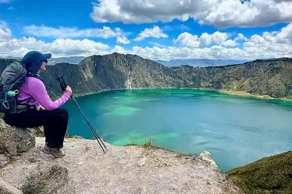 Hiker resting on the rim of the Quilotoa Loop crater lake