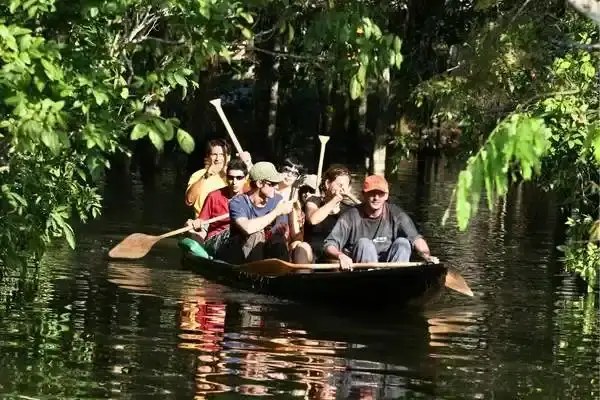 Travelers paddling a canoe through a flooded Amazon rainforest channel