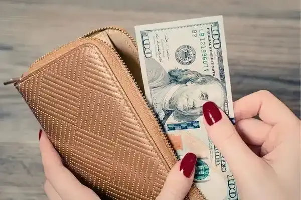 Traveler holding US dollar bills and a wallet to budget an Amazon trip