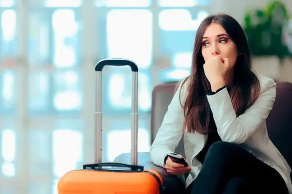 Traveler with luggage waiting anxiously at an airport before a flight