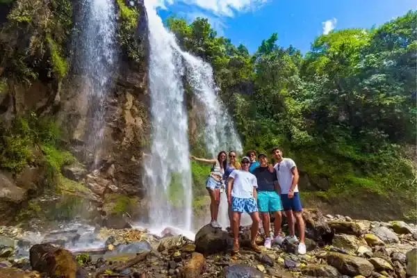 Friends posing on rocks at Pailon del Diablo waterfall near Banos, Ecuador