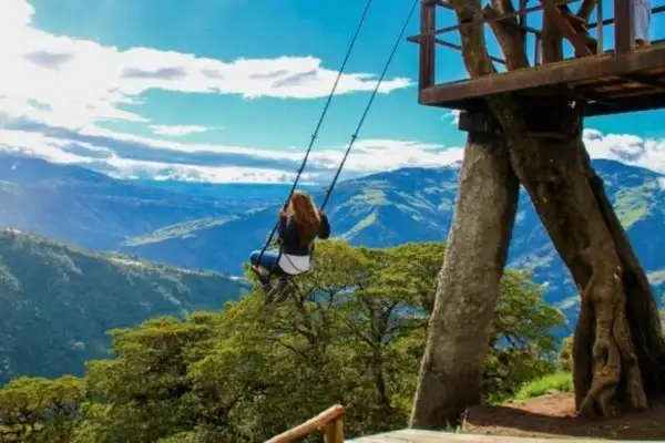 Woman on the Casa del Arbol swing overlooking the Tungurahua valley near Banos