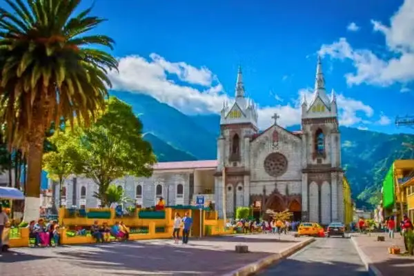 Banos main square with palm trees and the town cathedral on a sunny day