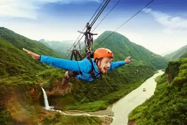 Zipliner soaring over Banos canyon and waterfall on a jungle adventure ride