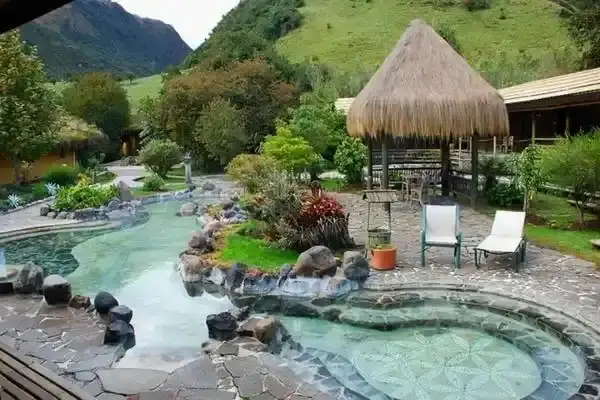 Thatched-roof gazebo beside curved thermal pools at a Papallacta hot springs resort