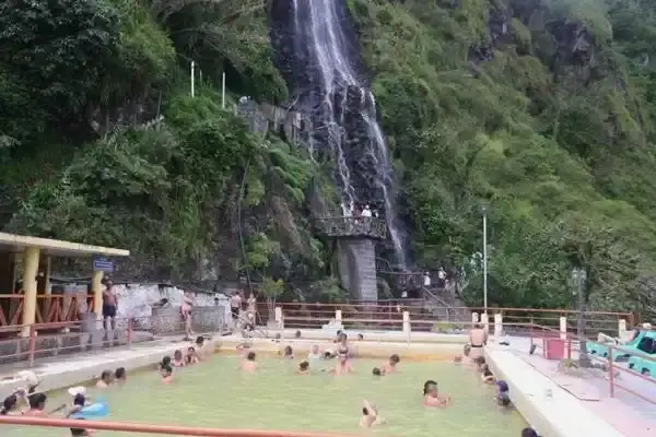 Piscinas de la Virgen thermal pools fed by a waterfall at Banos hot springs, Ecuador