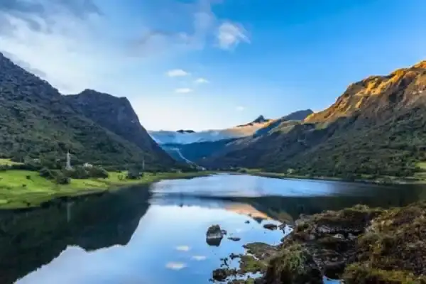 Highland lake in the Papallacta valley reflecting green mountains and morning mist