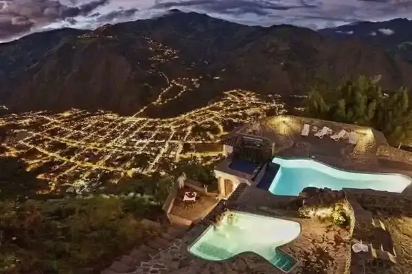 Aerial night view of Banos town lights with hotel thermal pools in the foreground