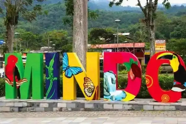 Colorful Mindo town sign decorated with toucan and hummingbird artwork