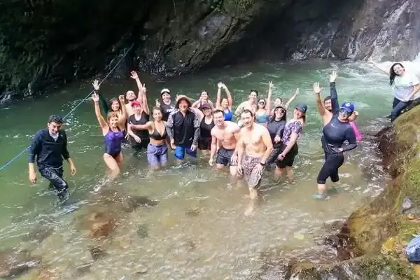 Group of travelers celebrating in a river pool below a Mindo waterfall