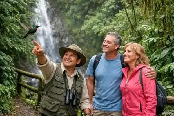 Local guide pointing out a hummingbird to travelers at a Mindo waterfall