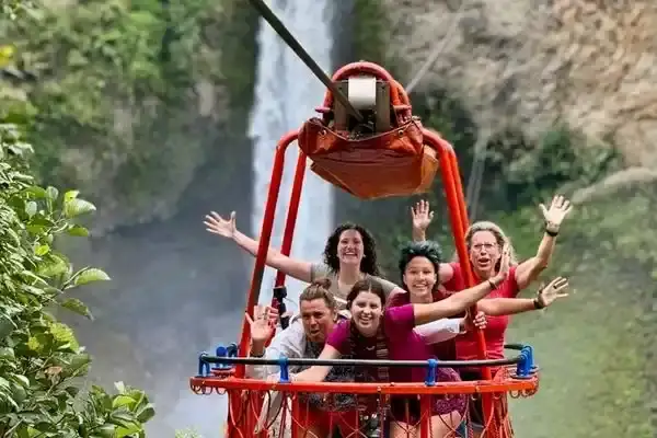 Group cheering on the giant swing above Pailon del Diablo waterfall near Banos