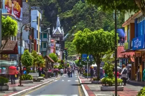 Main street of Banos with the church tower and green mountains behind town