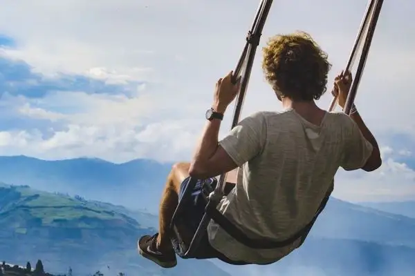 Visitor swinging over the Andes on a mountaintop swing near Banos
