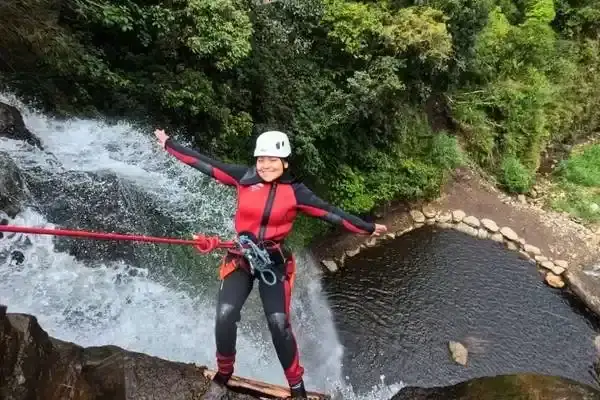 Canyoner rappelling down a waterfall on a canyoning tour near Banos