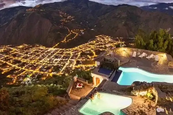 Aerial night view of Banos town lights and hillside thermal pools