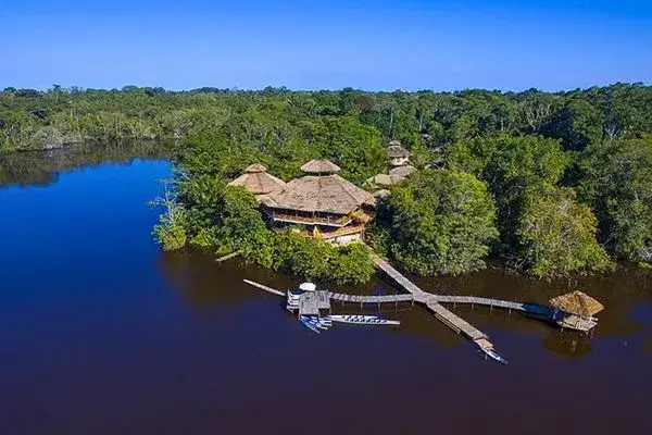 Aerial view of a thatched-roof Amazon lodge on a black-water lagoon in Ecuador