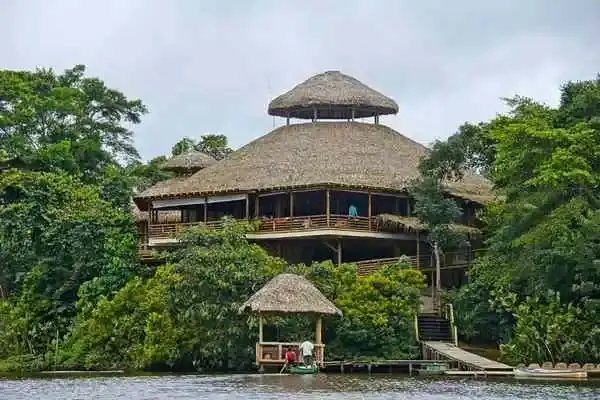 Three-story thatched lodge building rising above the Amazon rainforest canopy