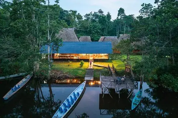 Canoes docked at an illuminated lodge deck in the Cuyabeno Wildlife Reserve at dusk