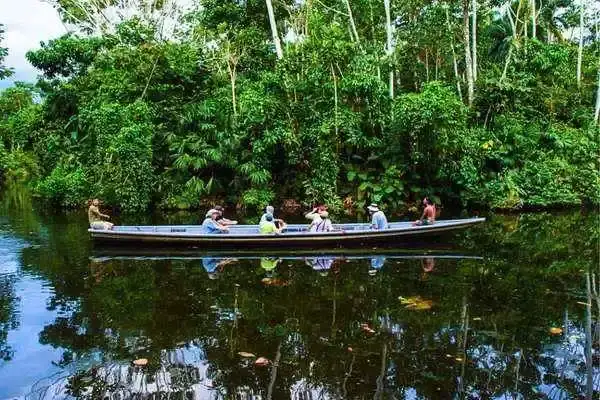 Guide and travelers paddling a canoe along a jungle river in the Ecuadorian Amazon