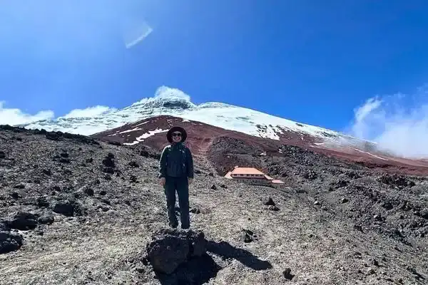 Hiker standing below Cotopaxi's steaming crater near the Jose Rivas refuge