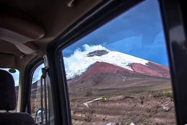 View of snow-capped Cotopaxi volcano through a tour van window on the way from Quito