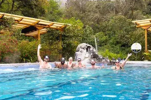 Group of friends waving and smiling in a thermal pool at Papallacta hot springs
