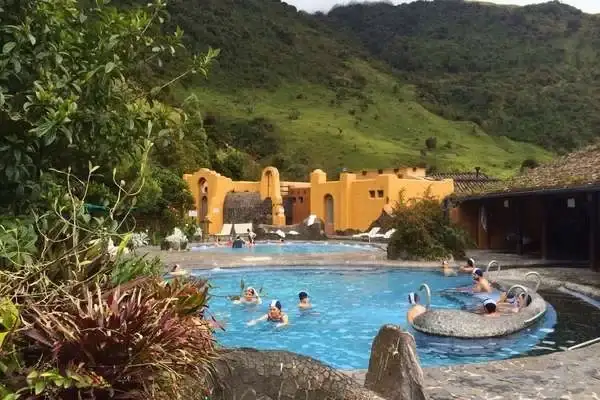 Bathers swimming in the thermal pools of Papallacta Ecuador with green mountains behind the resort