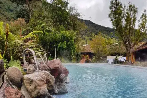 Rock waterfall feature flowing into a steaming thermal pool at Papallacta hot springs Ecuador