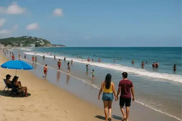 Couple walking along a sunny Ecuadorian coast beach with beachgoers in the water