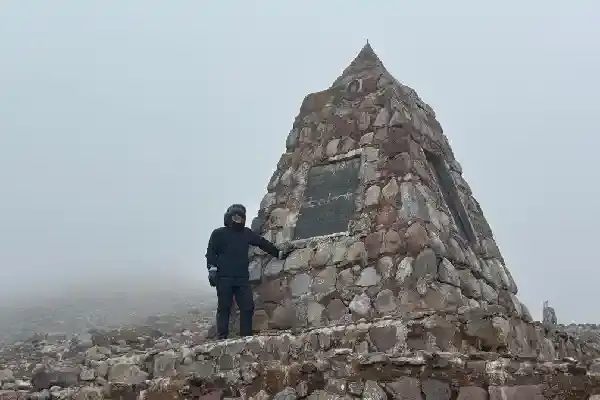 Viajero junto al monumento de piedra en la niebla del Chimborazo